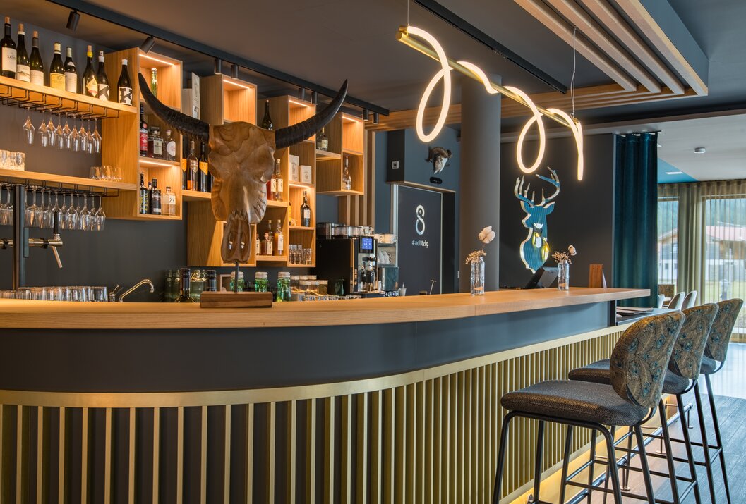 Bar mit Holztheke, Bullenschädel, Regalen mit Flaschen und dekorativer Beleuchtung
