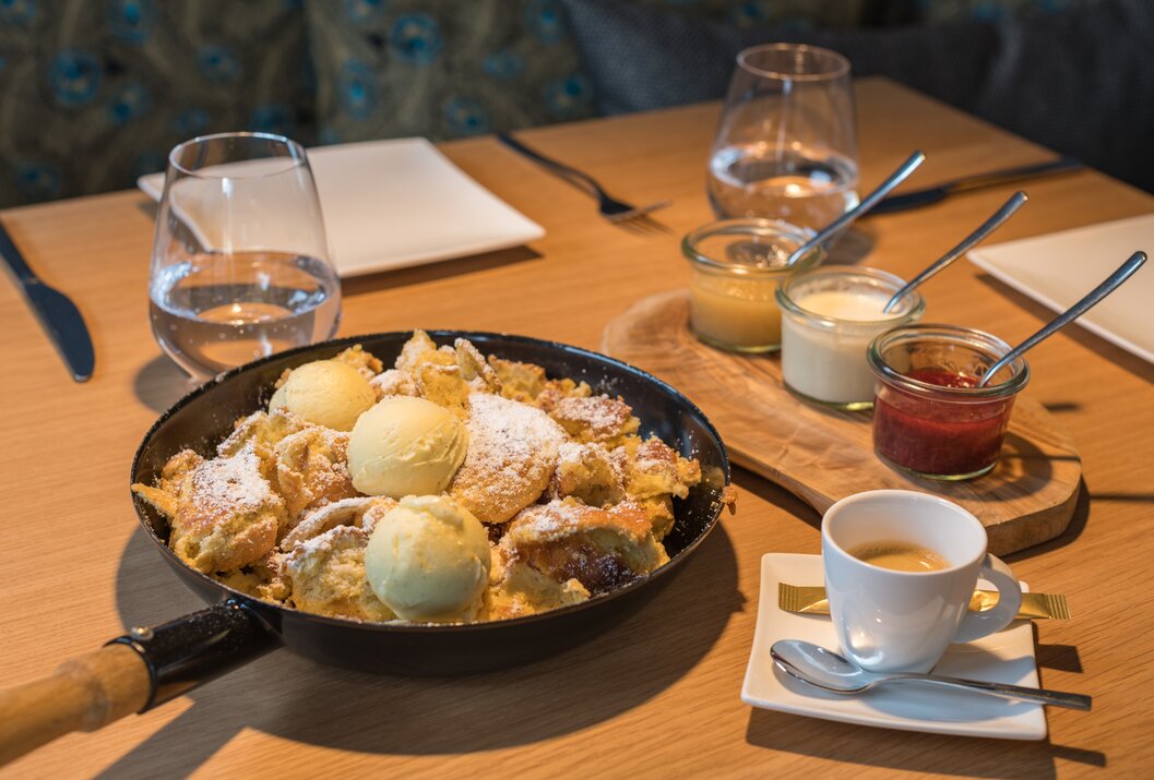 Kaiserschmarrn in Pfanne mit Puderzucker und Eis, dazu Dips und Espresso auf Holztisch