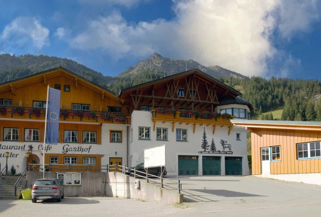 Gasthof vor Bergkulisse mit Hirsch-Motiv an der Fassade