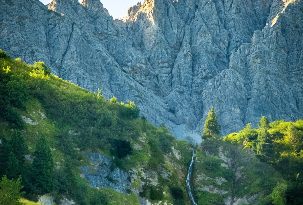 Berglandschaft mit grünen Hängen und Wasserfall im Vordergrund