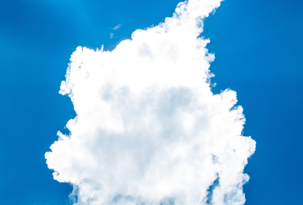 Wolke über Bergspitze vor blauem Himmel