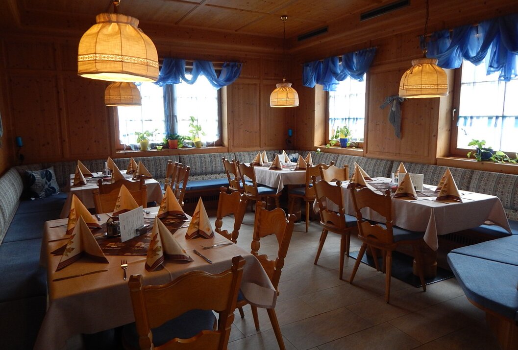 Holzvertäfeltes Restaurant mit gedeckten Tischen und blauen Vorhängen