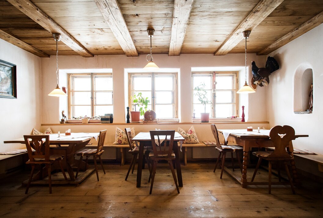 Gemütliches Restaurant mit Holztischen, Stühlen, Fensterfront und rustikaler Holzdecke