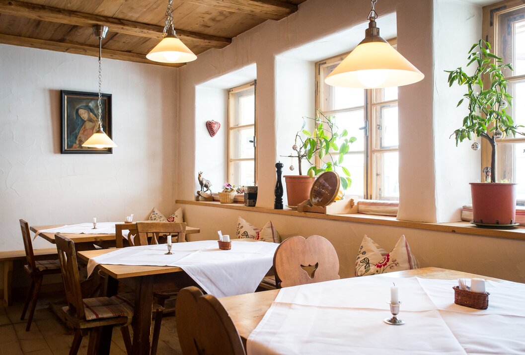 Gemütliches Restaurant mit Holztischen, weißen Tischdecken und rustikalen Lampen