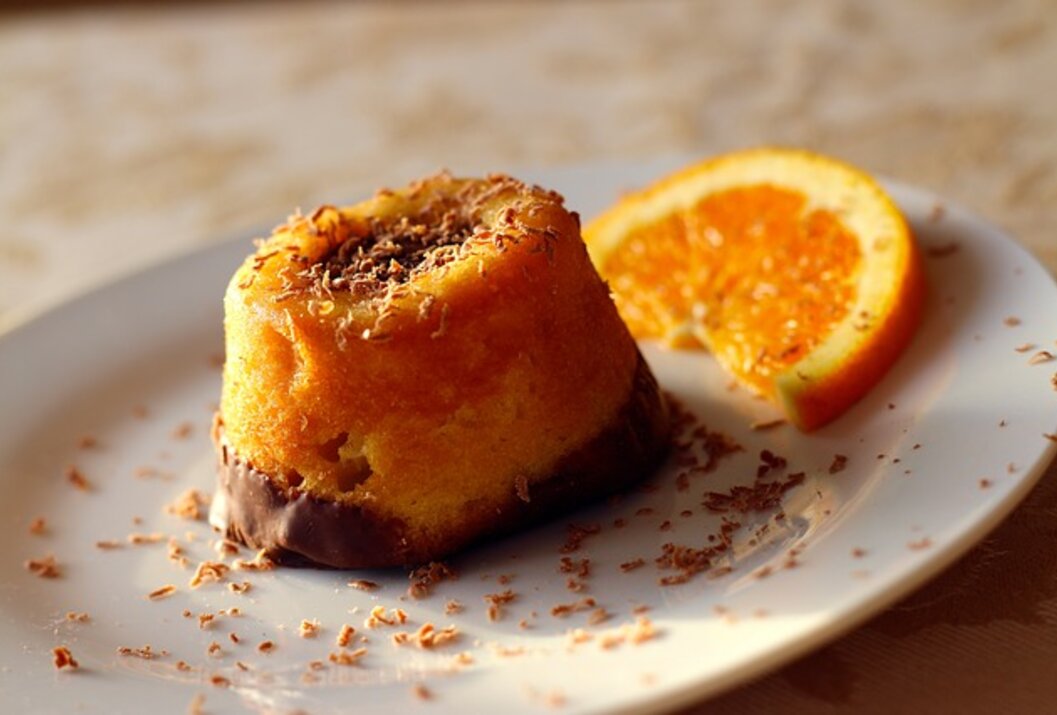 Kleiner Kuchen mit Schokoladenglasur und Orangenscheibe auf einem Teller