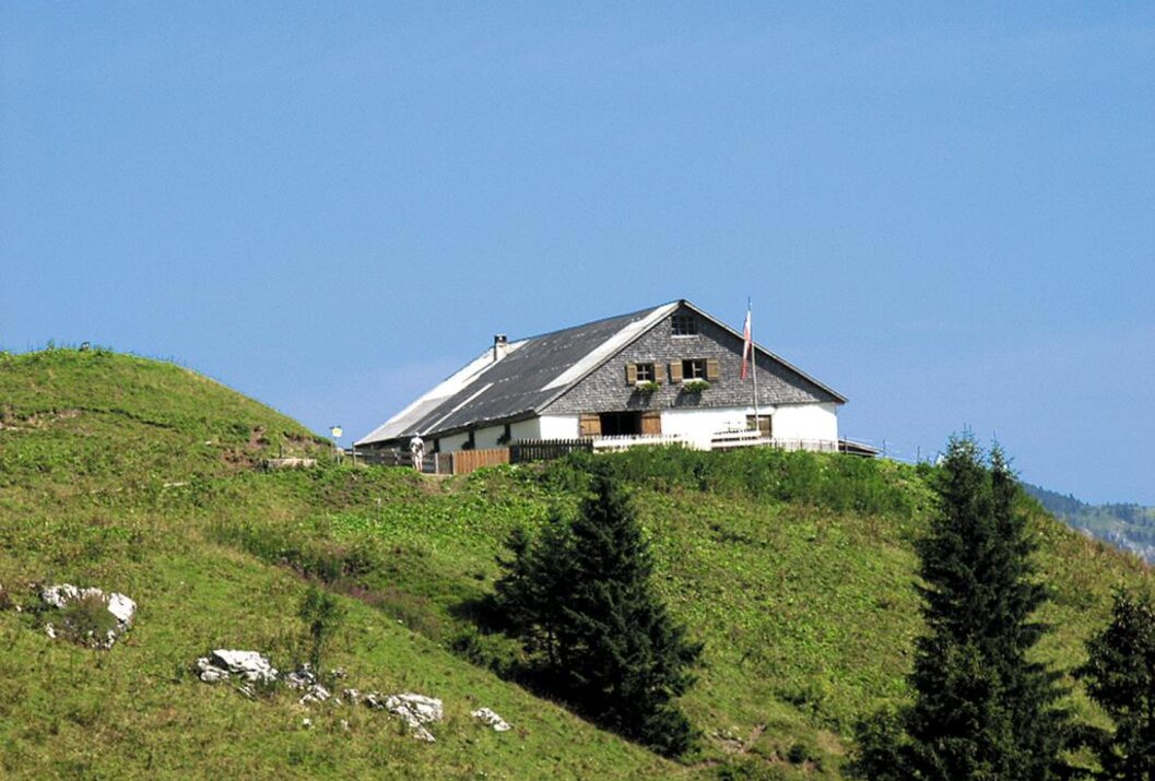 Hütte auf einem grünen Hügel unter blauem Himmel
