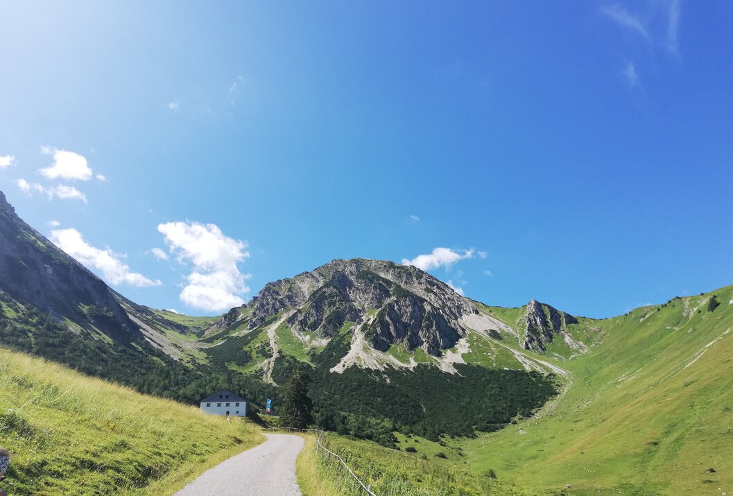 Berglandschaft mit Weg, Haus und blauem Himmel