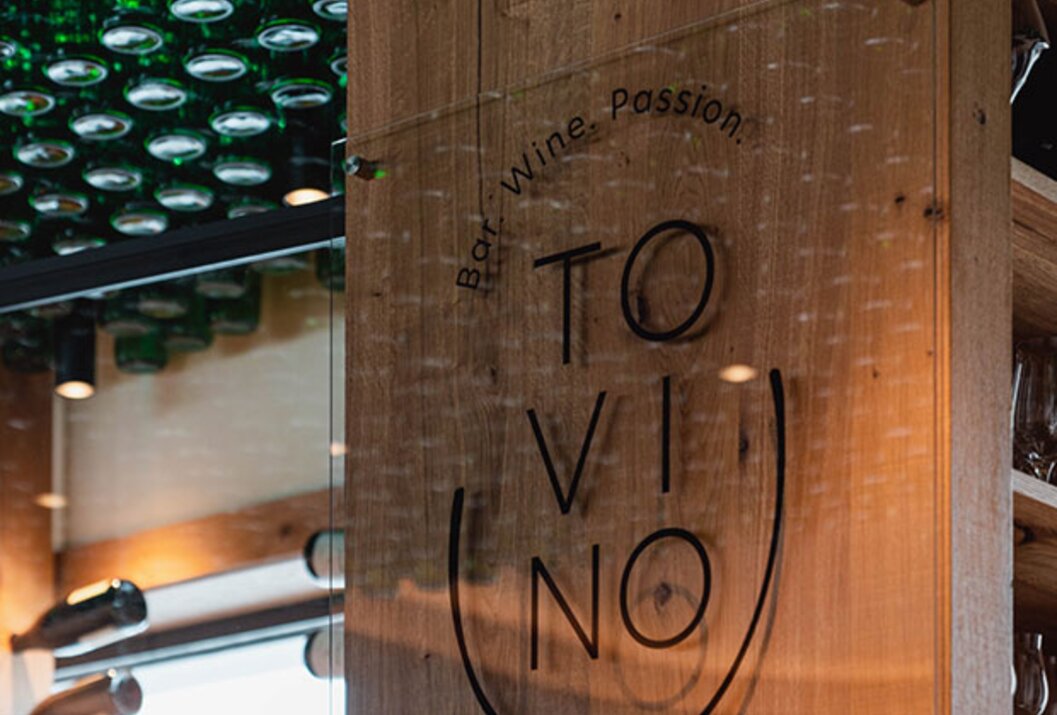 Bar Tovino Schild vor Holzwand, Flaschen an Decke und Wand