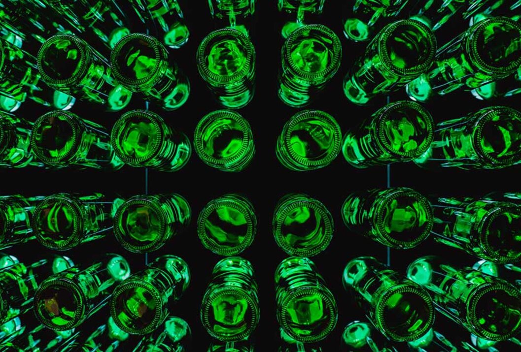 Grüne Glasflaschen von unten in quadratischer Anordnung auf schwarzem Hintergrund