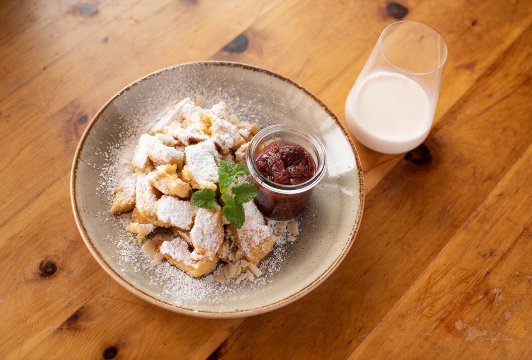 Kaiserschmarrn mit Puderzucker, Marmelade und Milch auf einem Teller
