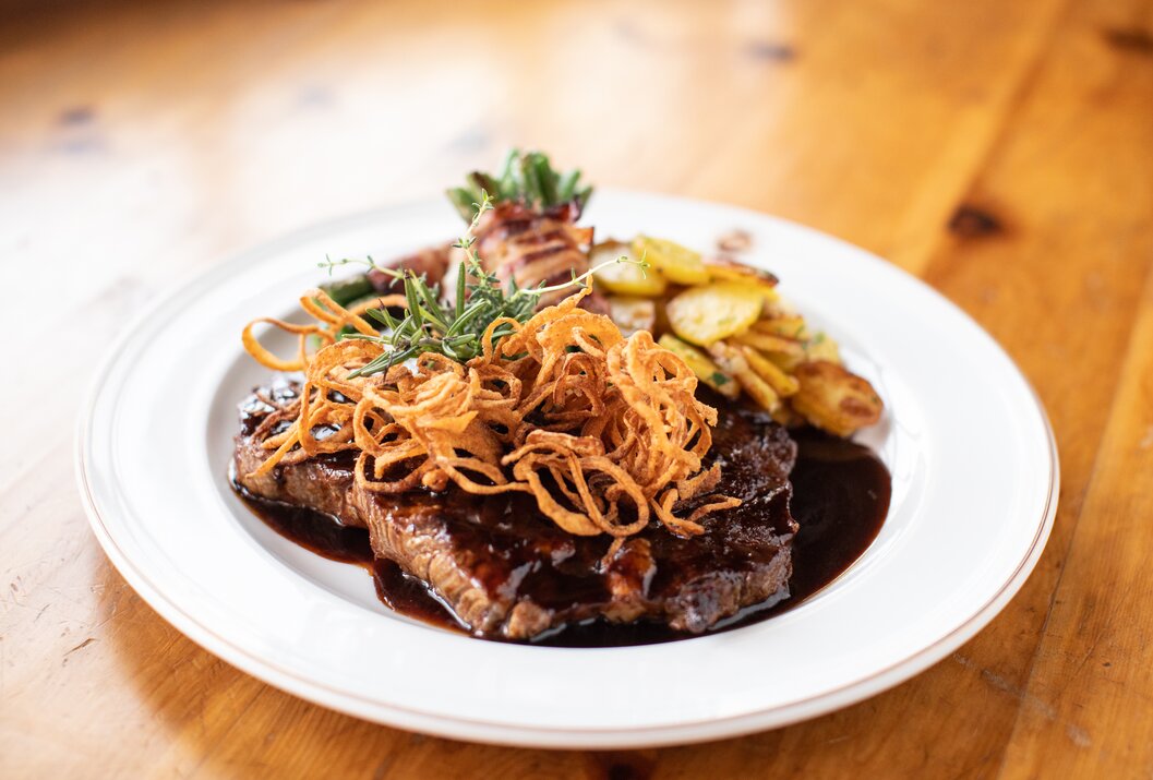 Teller mit Steak, Bratkartoffeln, Röstzwiebeln und Soße