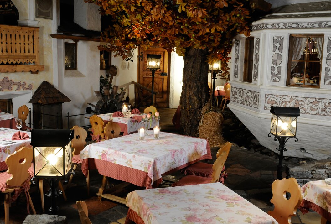 Restaurant mit gedeckten Tischen unter einem Baum mit Herbstlaub