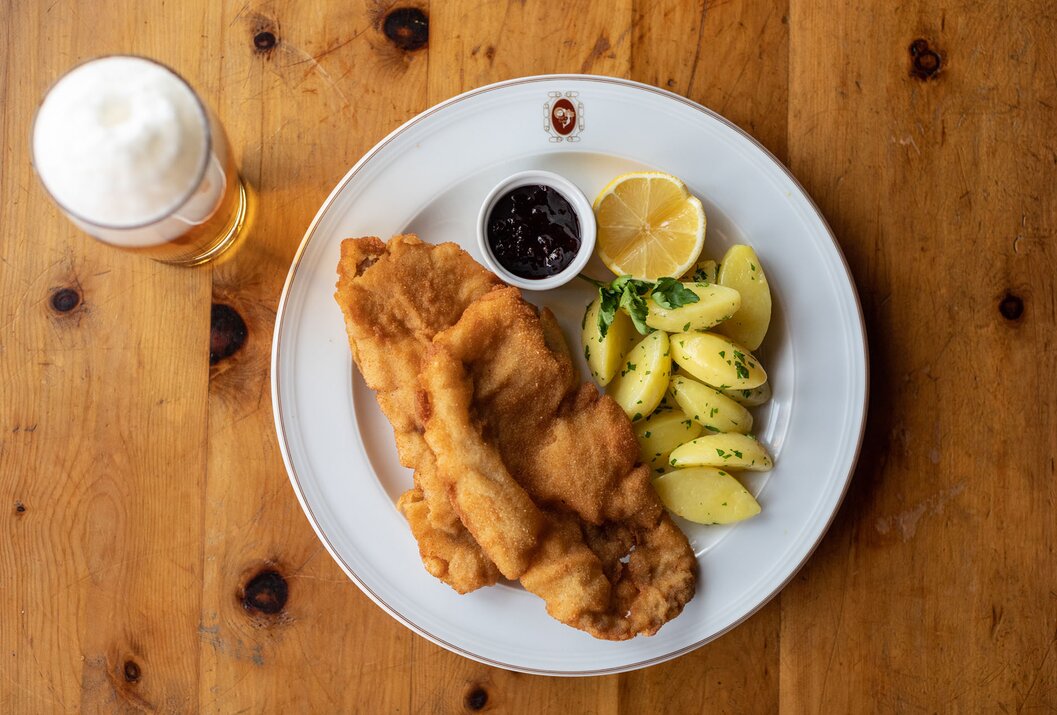 Wiener Schnitzel mit Kartoffeln, Zitrone und Preiselbeeren auf Teller