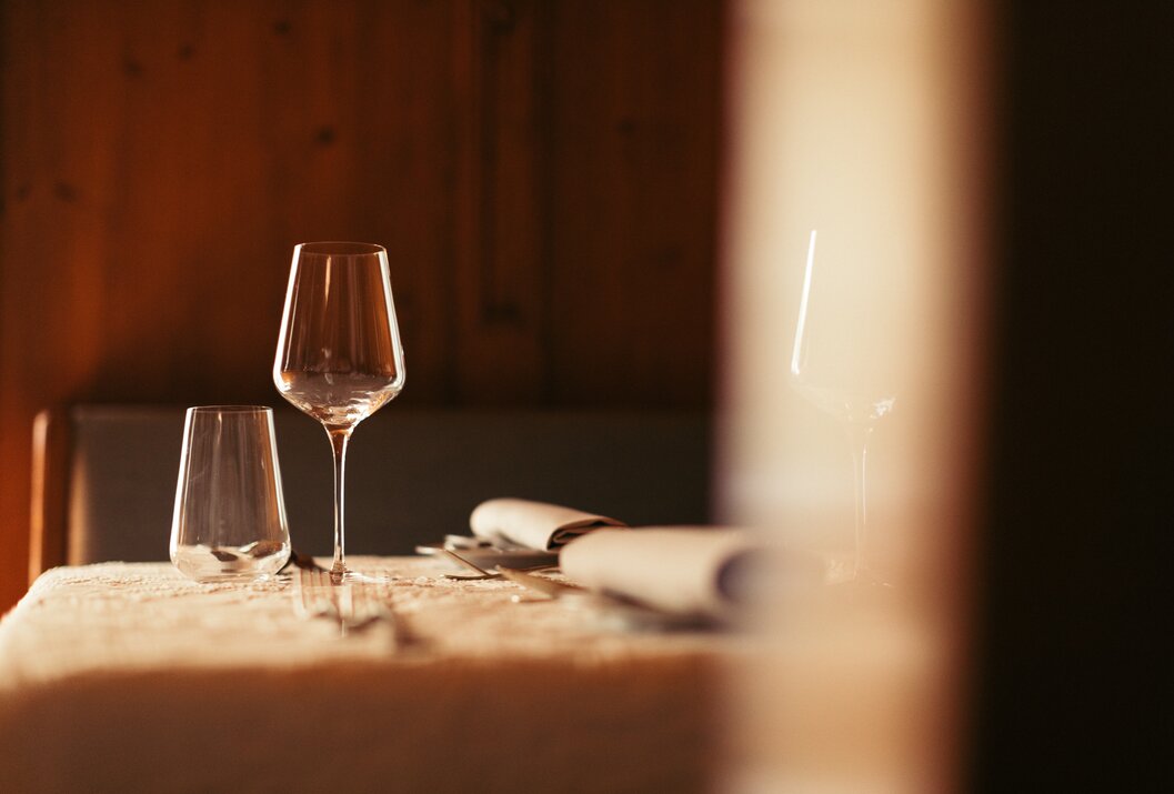 Gedeckter Tisch mit Weingläsern und Besteck im warmen Licht
