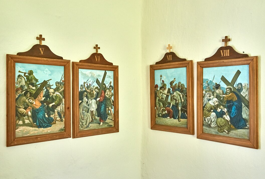 Vier gerahmte Kreuzwegstationen hängen an einer hellen Wand
