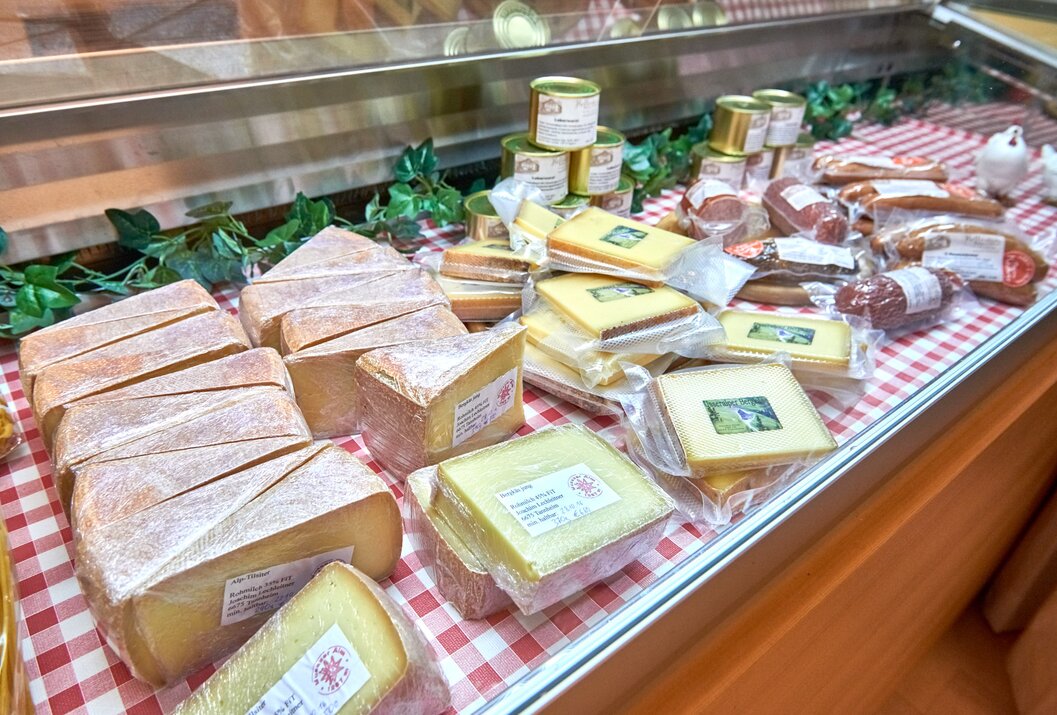 Käse, Wurst und Konserven in einer Auslage mit rot-weiß kariertem Tuch