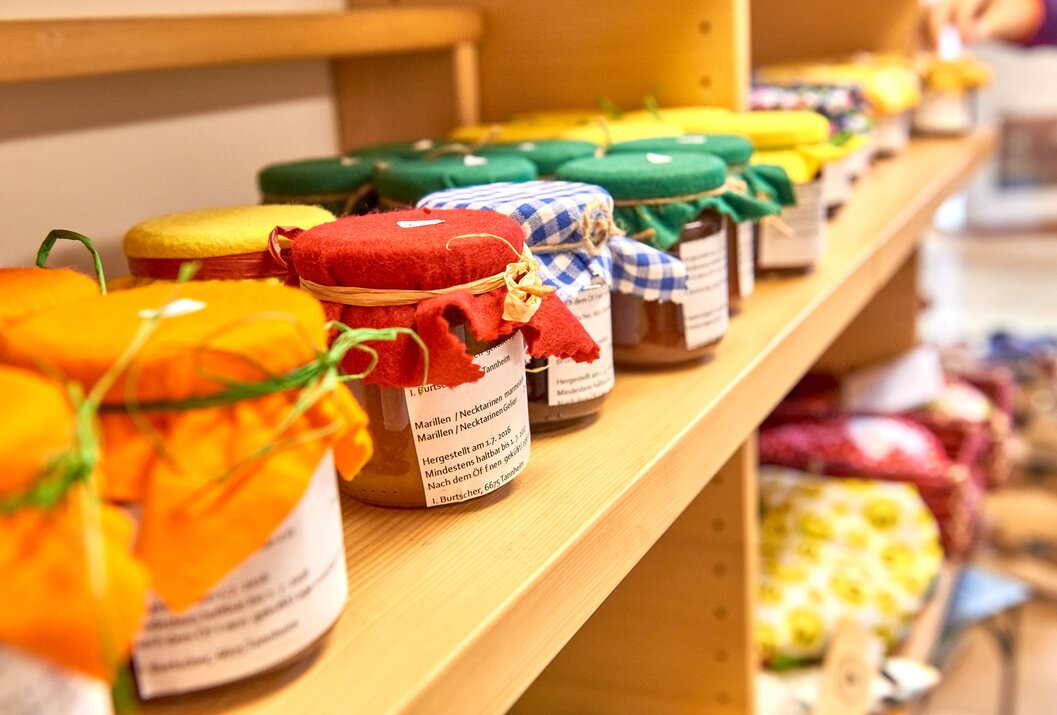 Regal mit Gläsern Marmelade und Konfitüre mit bunten Stoffdeckeln