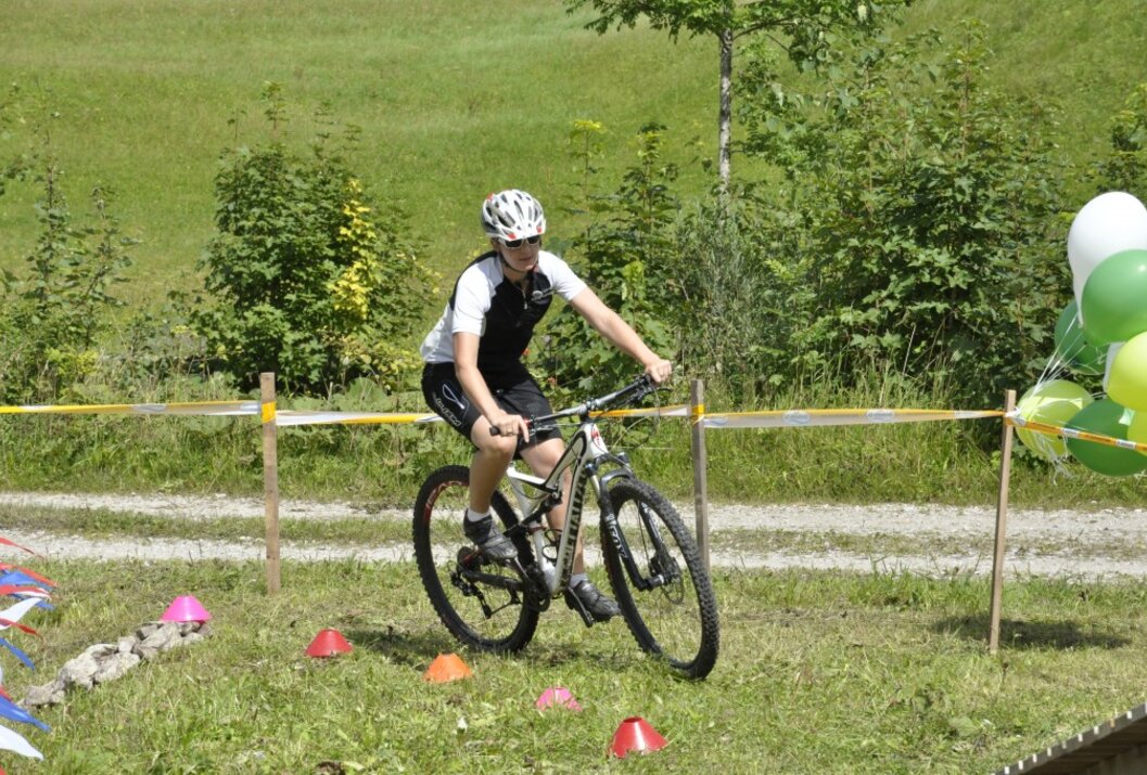 Mountain biker with helmet rides slalom on a meadow