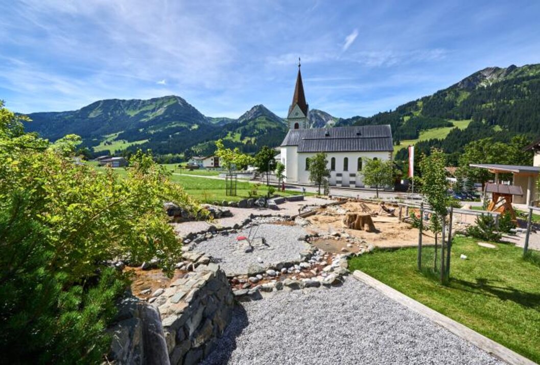 Kirche in Berglandschaft mit Spielplatz im Vordergrund