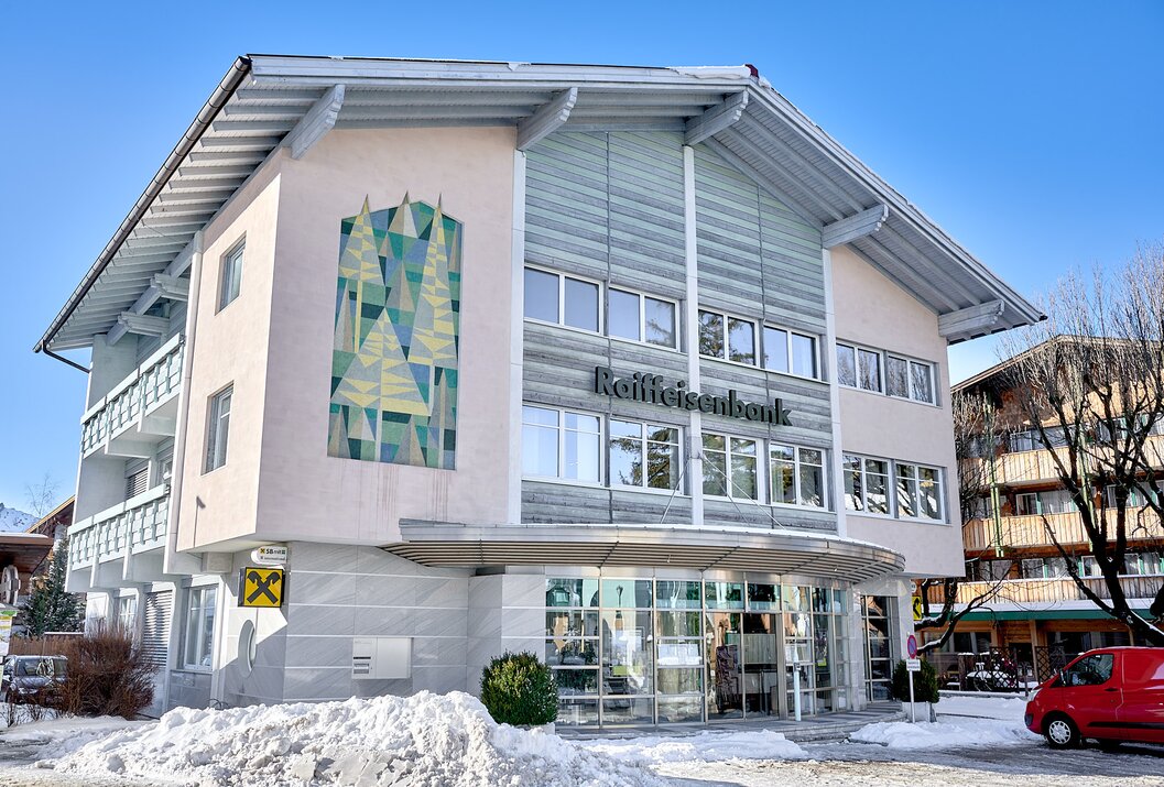 Raiffeisenbank-Gebäude mit moderner Fassade und Schneehaufen davor