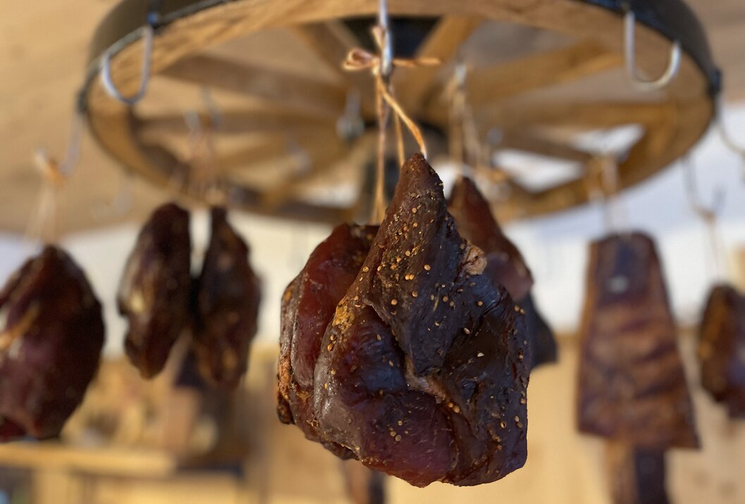Geräuchertes Fleisch hängt an einem Holzrad von der Decke