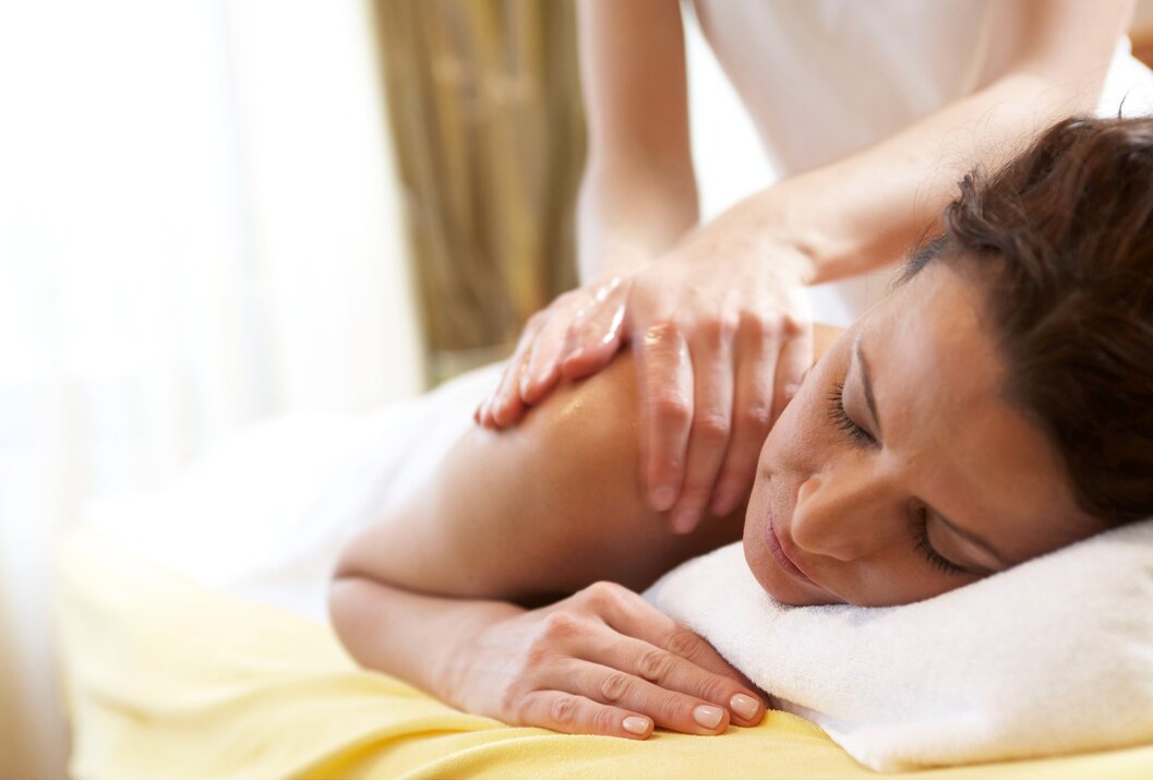 Frau liegt auf dem Bauch und bekommt eine Rückenmassage