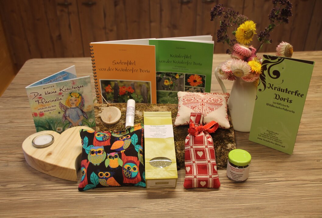 Arrangement mit Büchern, Kissen, Tee, Creme, Blumen und Deko auf Moos