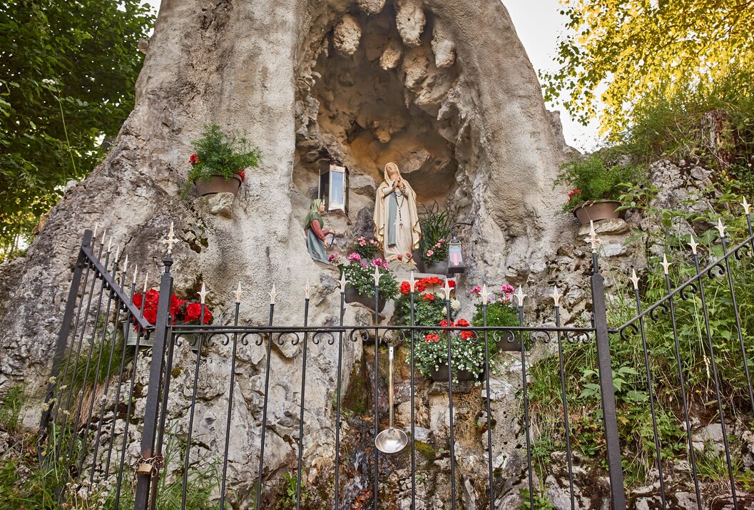 Mariengrotte mit Statue, Blumen und Gitterzaun