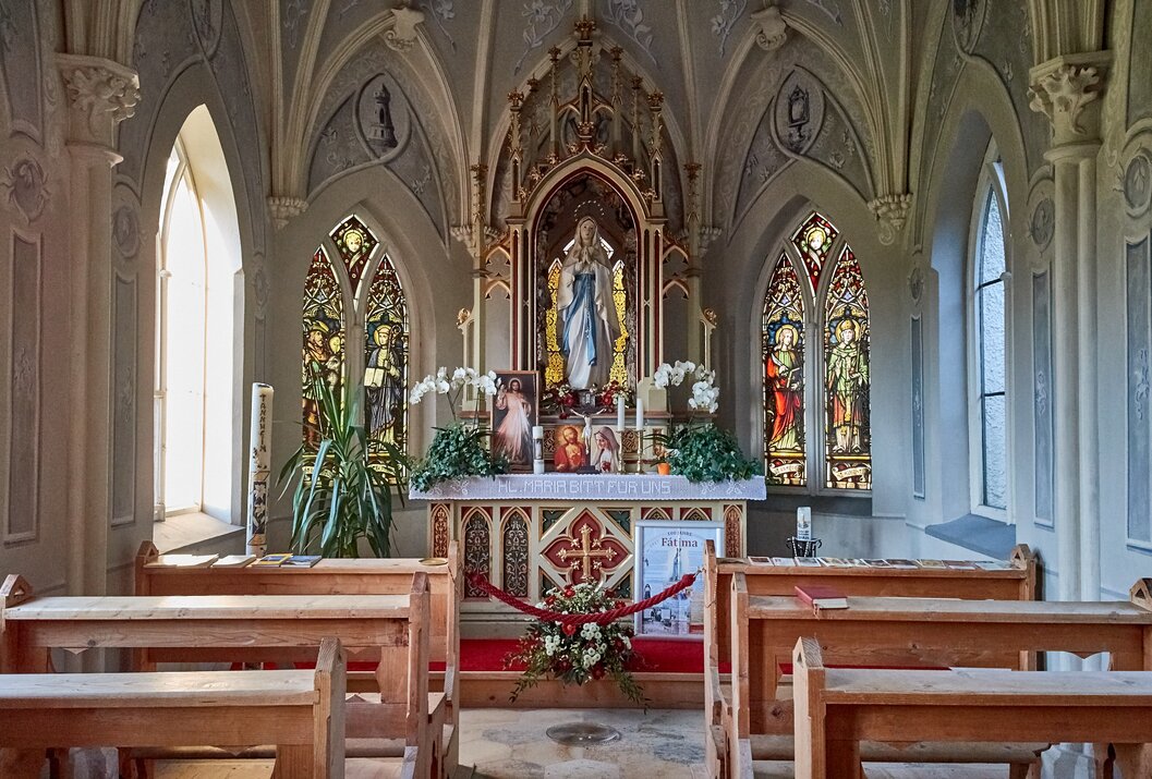 Innenansicht einer Kapelle mit Altar, Marienstatue und Buntglasfenstern