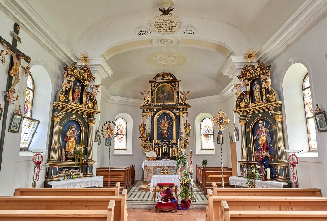 Innenansicht einer kleinen Kirche mit Altar und verzierten Seitenaltären