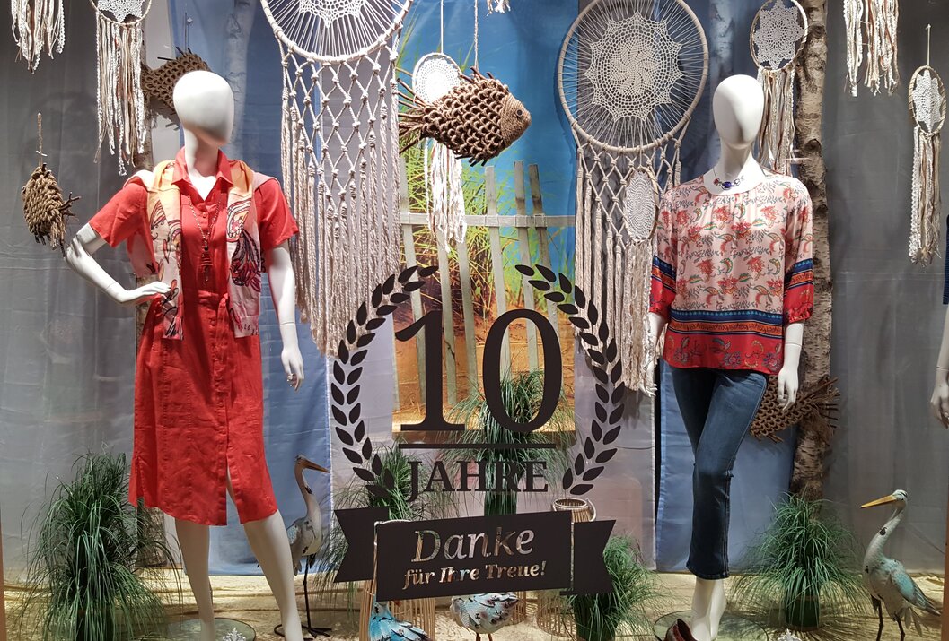 Shop window with clothing, dream catchers, decorative fish and a sign