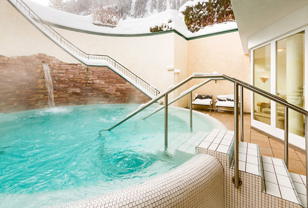 Turquoise outdoor pool with stairs and snow-covered surroundings