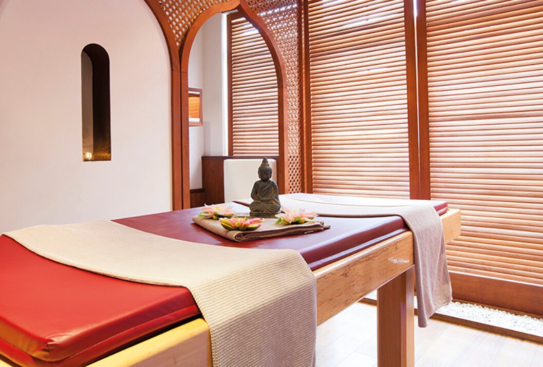 Massage table with Buddha statue and lotus flowers in a spa