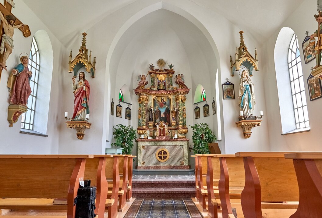 Interior view of a church with altar, saints and pews