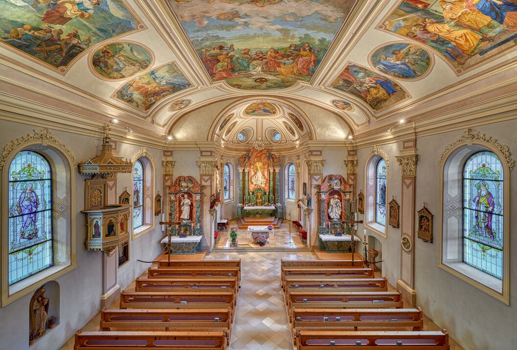 Innenansicht einer Kirche mit Bänken, Altar und Deckenmalerei