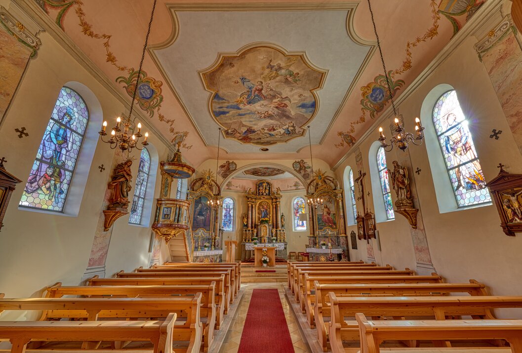 Innenansicht einer Kirche mit Bänken, Altar und Deckenmalerei