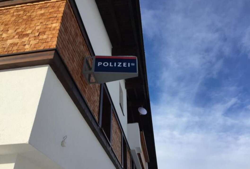 Polizeiwache mit blauem Schild vor weißem Gebäude unter blauem Himmel