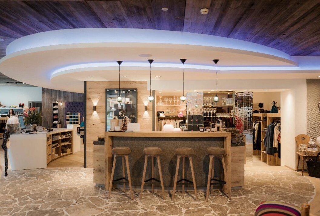 Bar mit vier Hockern, Holzdecke und Beleuchtung in einem Raum mit Steinfußboden