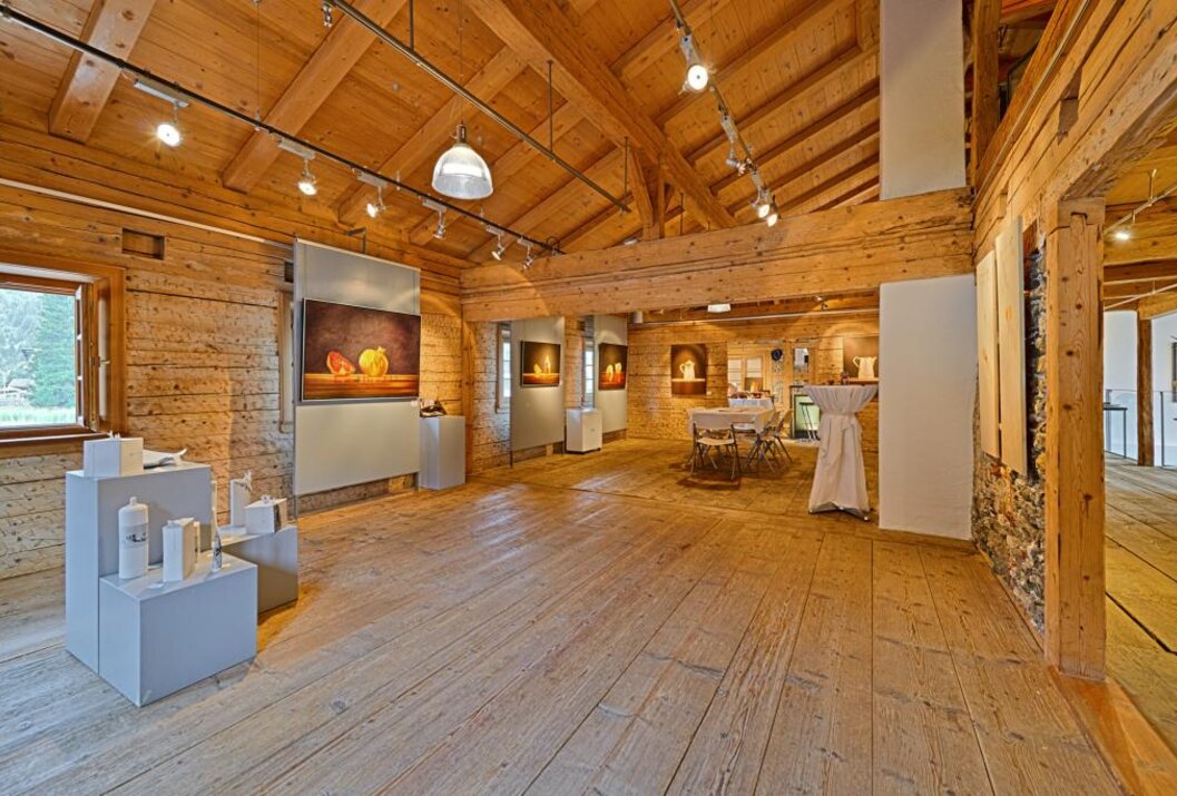 Holzvertäfelter Ausstellungsraum mit Gemälden und Tischen