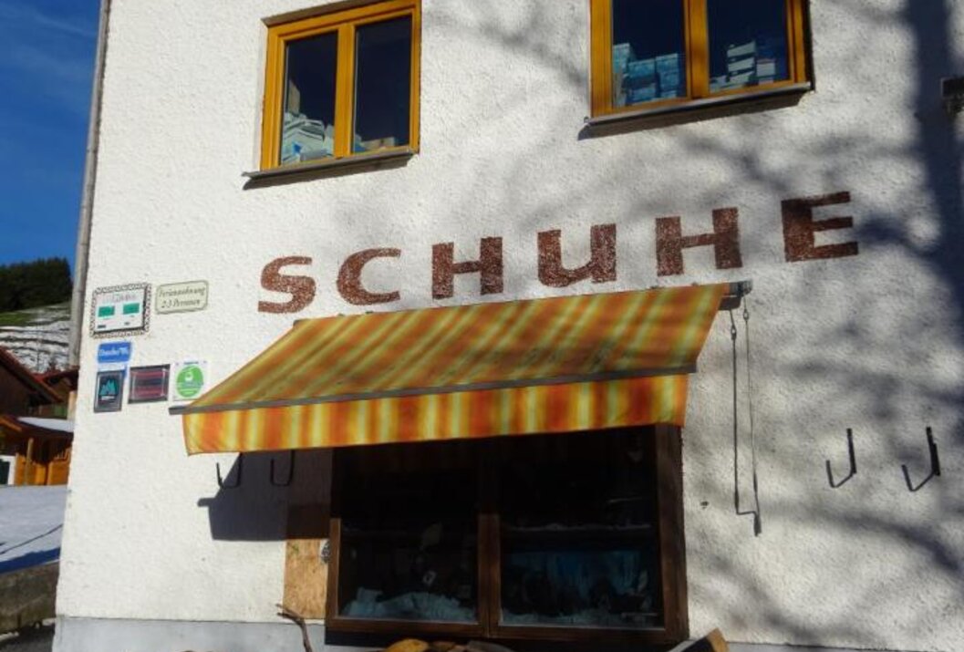 Fassade eines Schuhgeschäfts mit Markise und zwei Fenstern