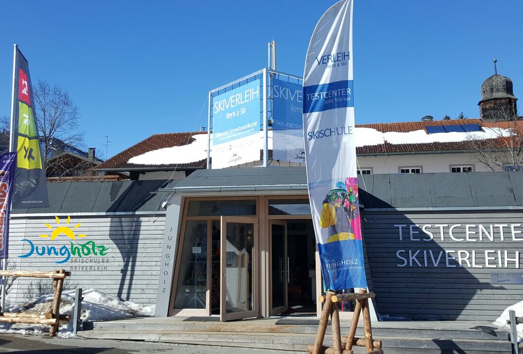 Skiverleih-Gebäude mit Fahne und Schildern bei strahlendem Sonnenschein