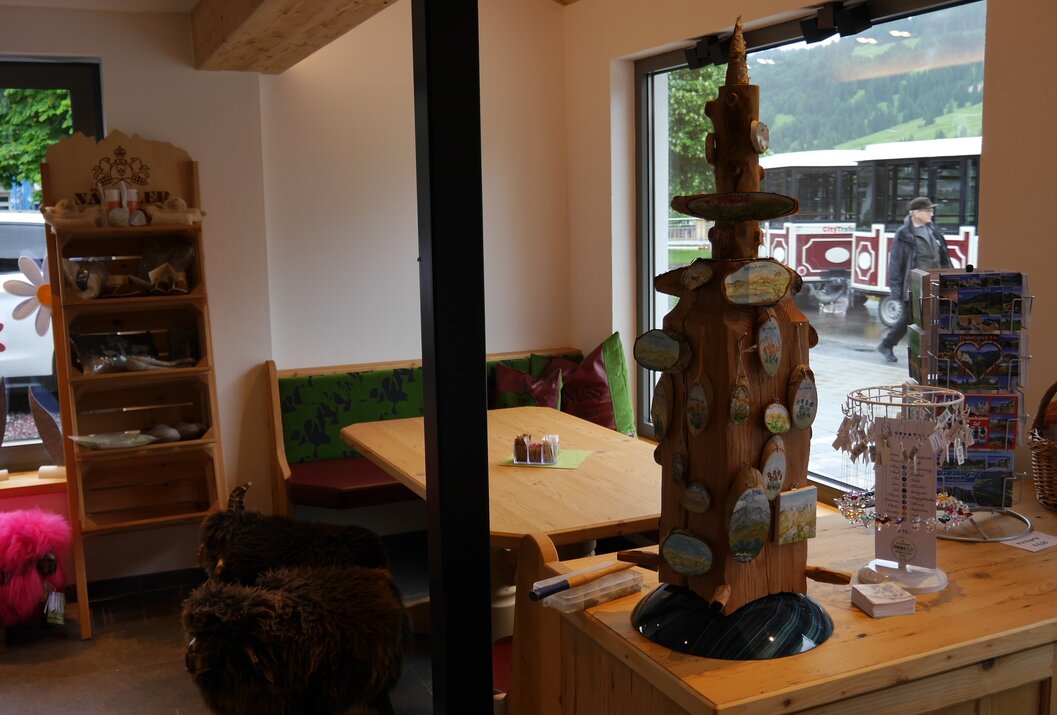 Holzfigur mit Hut und Schildern in einem Raum mit Sitzecke und Fenster