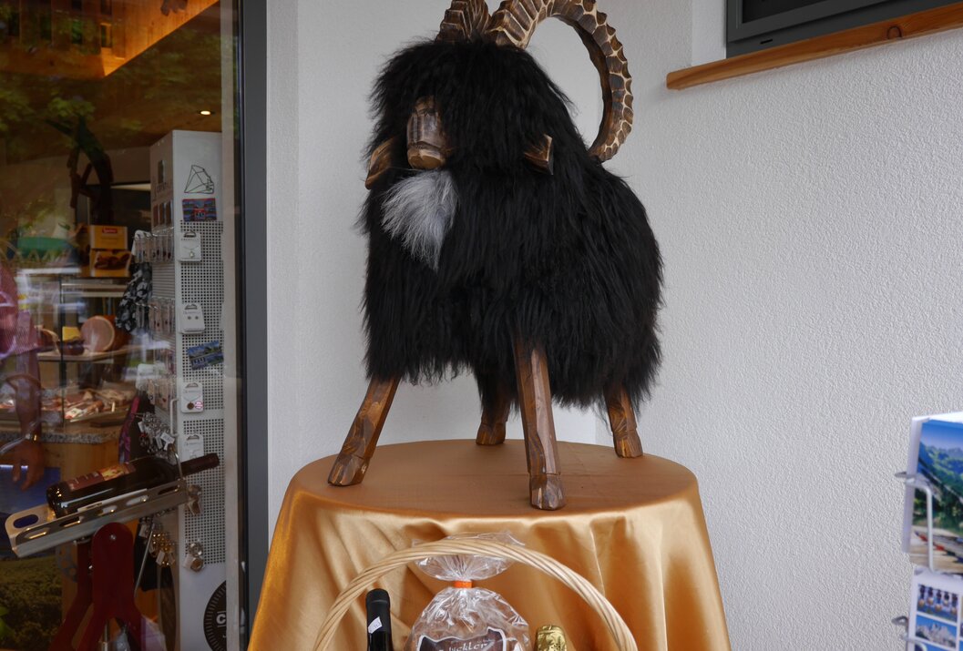 Schwarze Ziegen-Holzfigur mit großen Hörnern auf einem Tisch mit goldener Decke