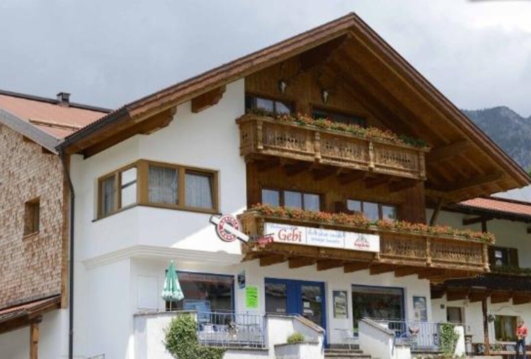 Haus mit Holzbalkon und Gebi-Schild über dem Eingang