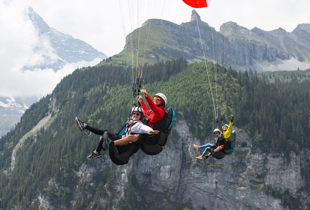 Zwei Tandem-Gleitschirmflieger vor Bergkulisse in der Luft