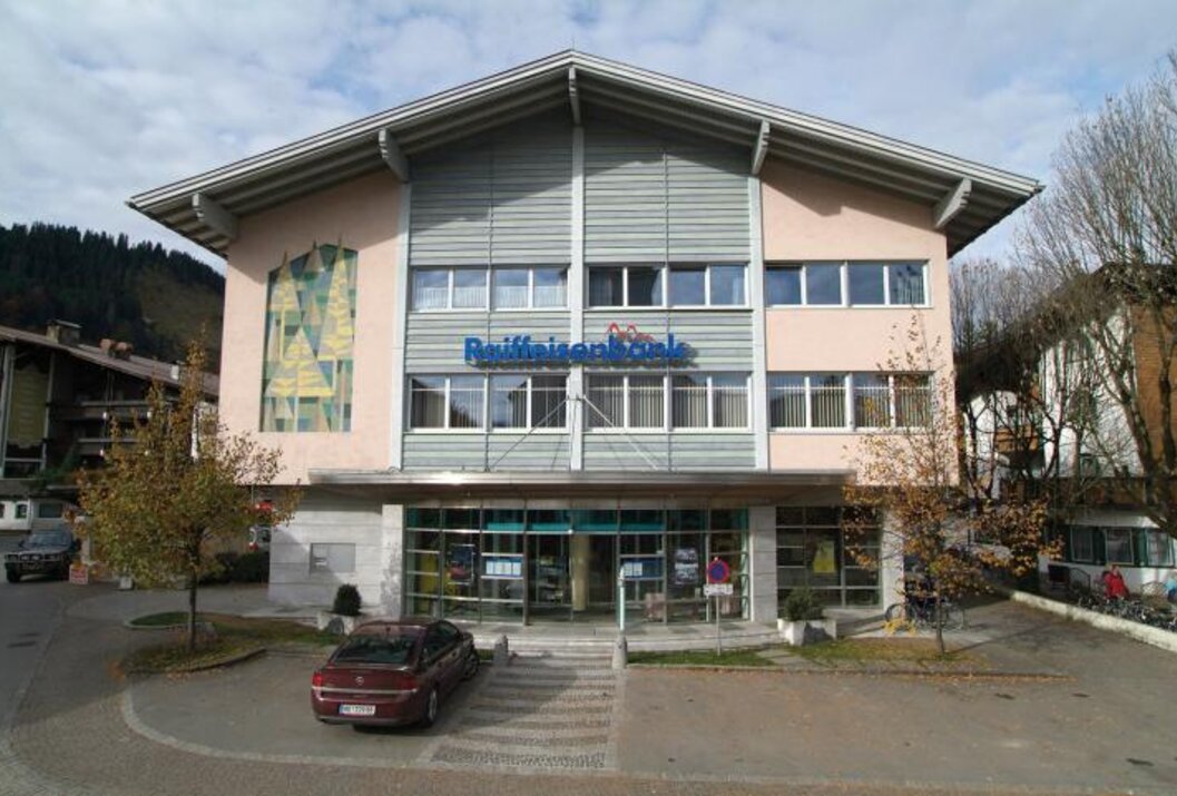 Raiffeisenbank-Gebäude mit großem Giebeldach und Parkplatz davor