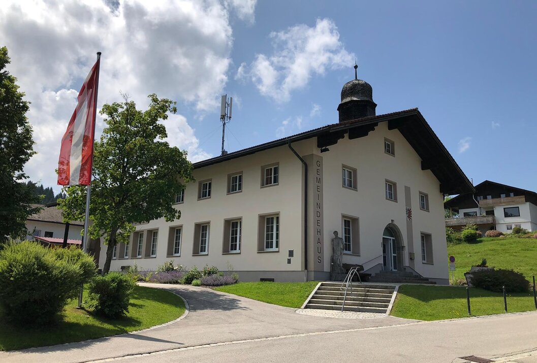 Gemeindehaus mit Fahne und Treppe an sonnigem Tag
