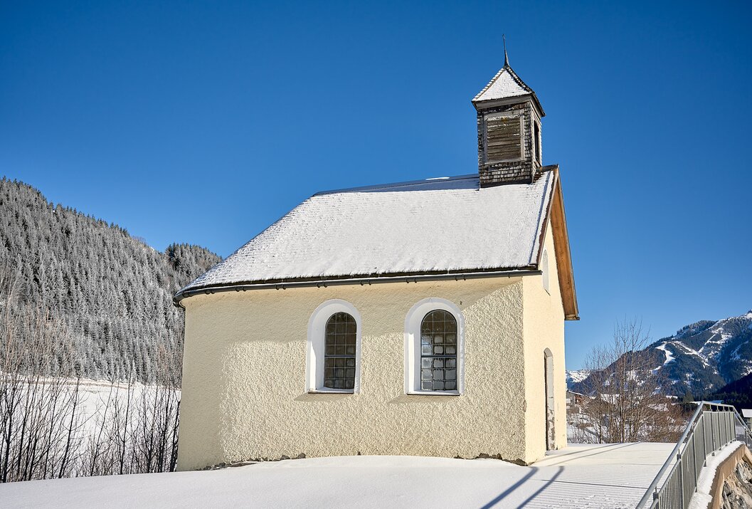 Kleine Kapelle im Schnee vor blauem Himmel