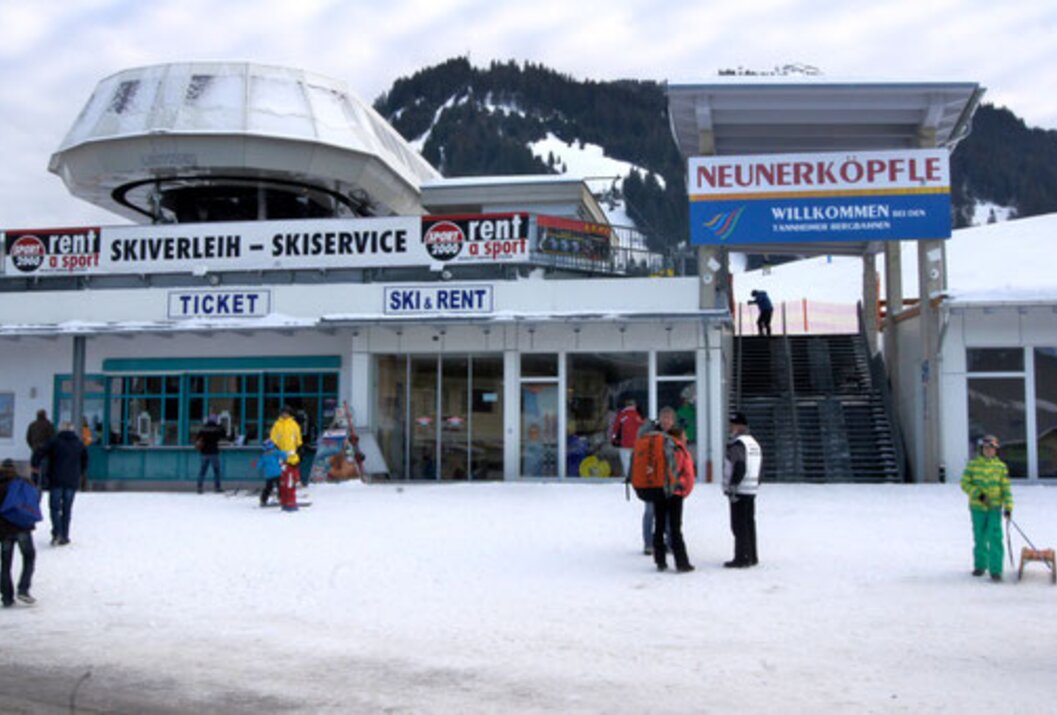 Skistation im Schnee mit Menschen und Schildern wie "Skiservice" und "Ski & Rent"