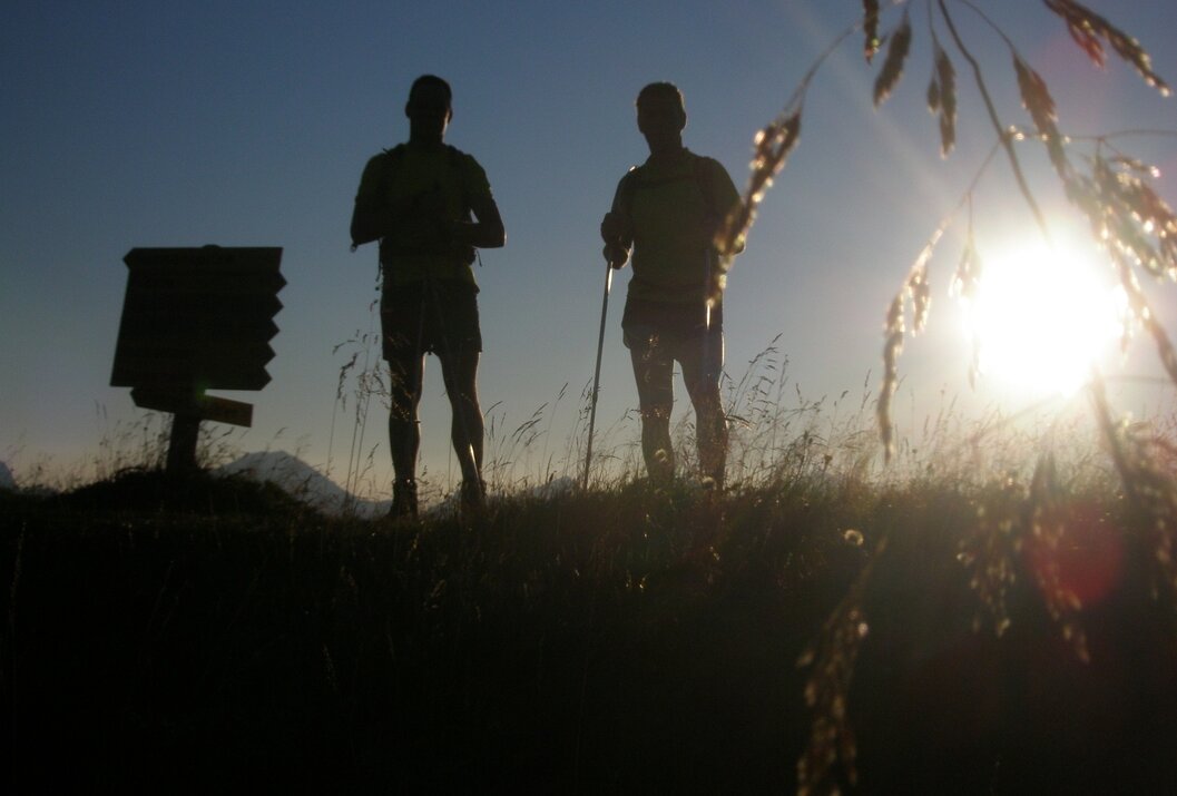 Zwei Wanderer Silhouetten im Gegenlicht auf Berggipfel